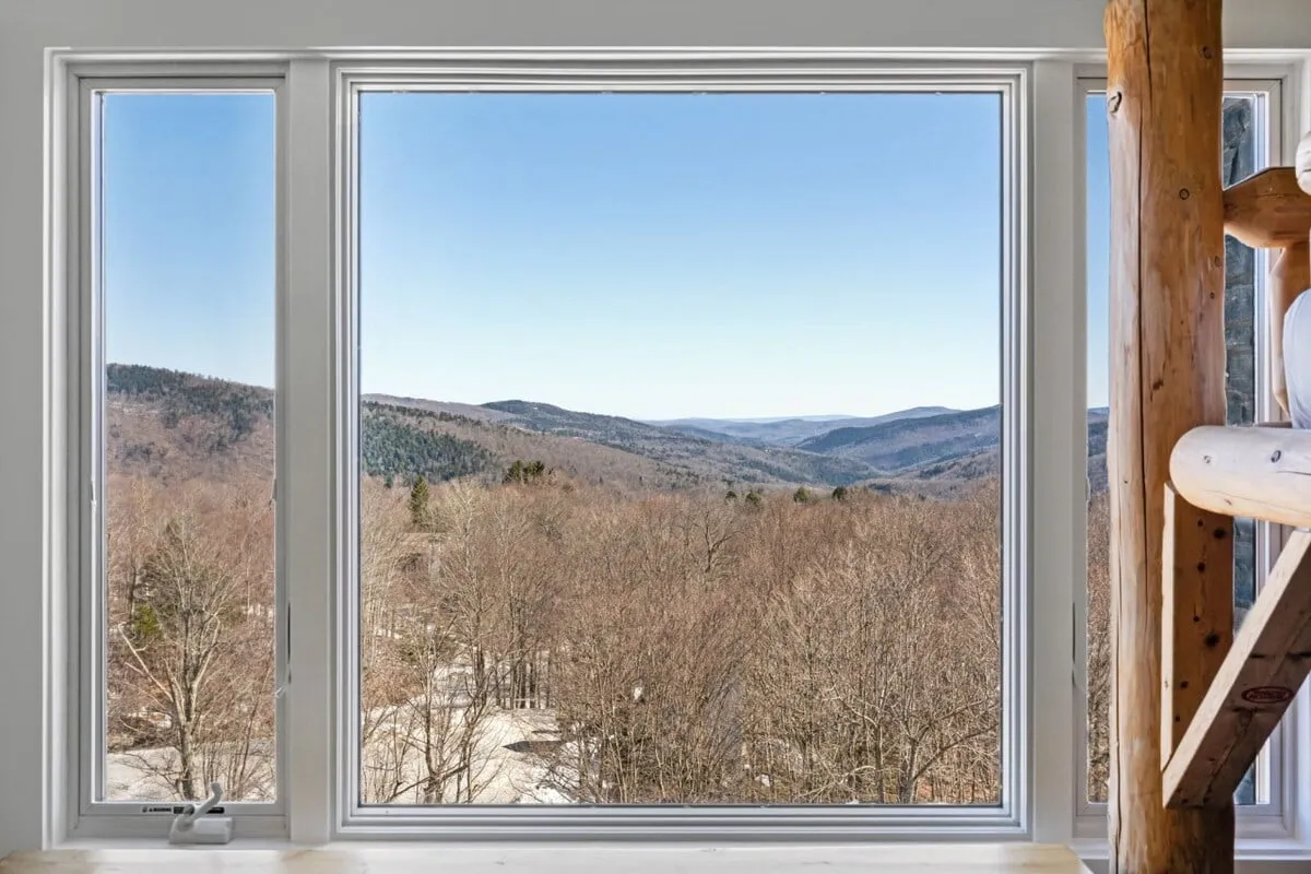 This image captures a tranquil mountainous landscape with bare trees and a clear sky, suggesting the beauty of the outdoors in non-winter months. The view showcases the serene natural setting, ideal for scenic drives, hiking, or simply enjoying Vermont's renowned foliage.