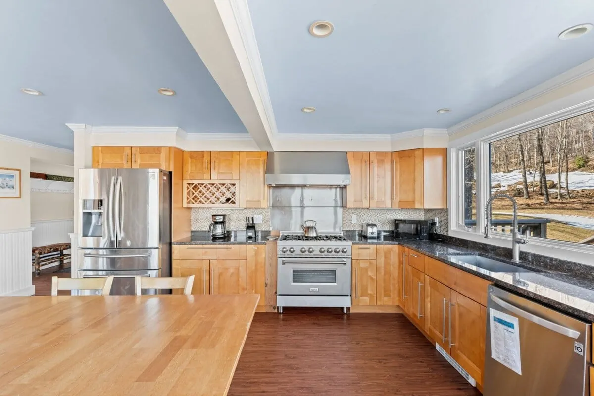A spacious, modern kitchen anchored by a large island and stainless steel appliances. Ample natural light pours in through bright windows, making the kitchen an inviting hub for both cooking and entertaining.